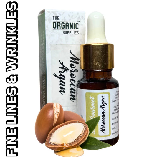 A glass dropper bottle of "Moroccan Argan Oil" sits on a white background, next to a small, square cardboard box. Text on the bottle includes "THE ORGANIC SUPPLIES," "100% Pure Organic Carrier Oil," "FINE LINES & WRINKLES.